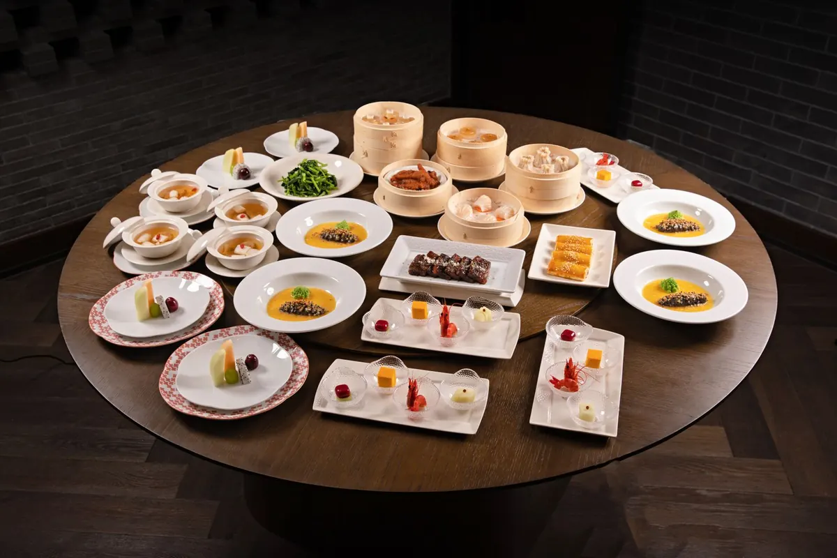 A round table laid with many shared dishes including dumplings and soups