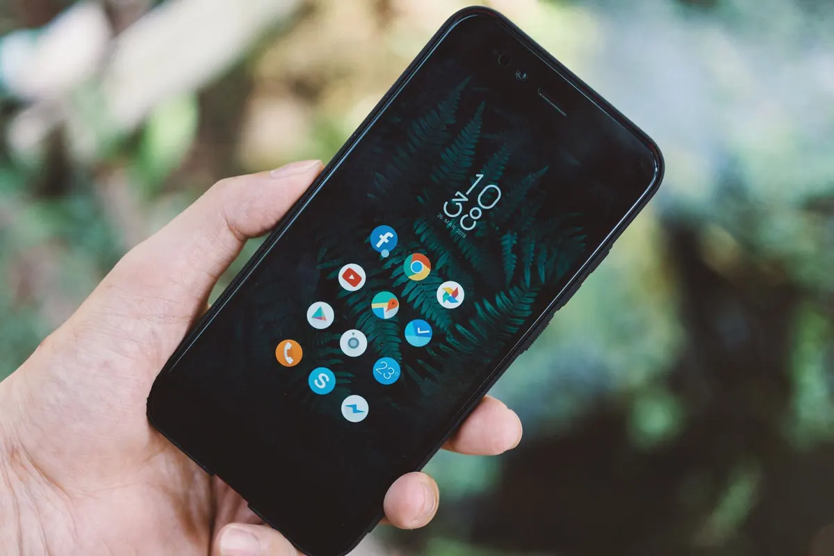 A hand holding a smartphone showing a screen of app icons