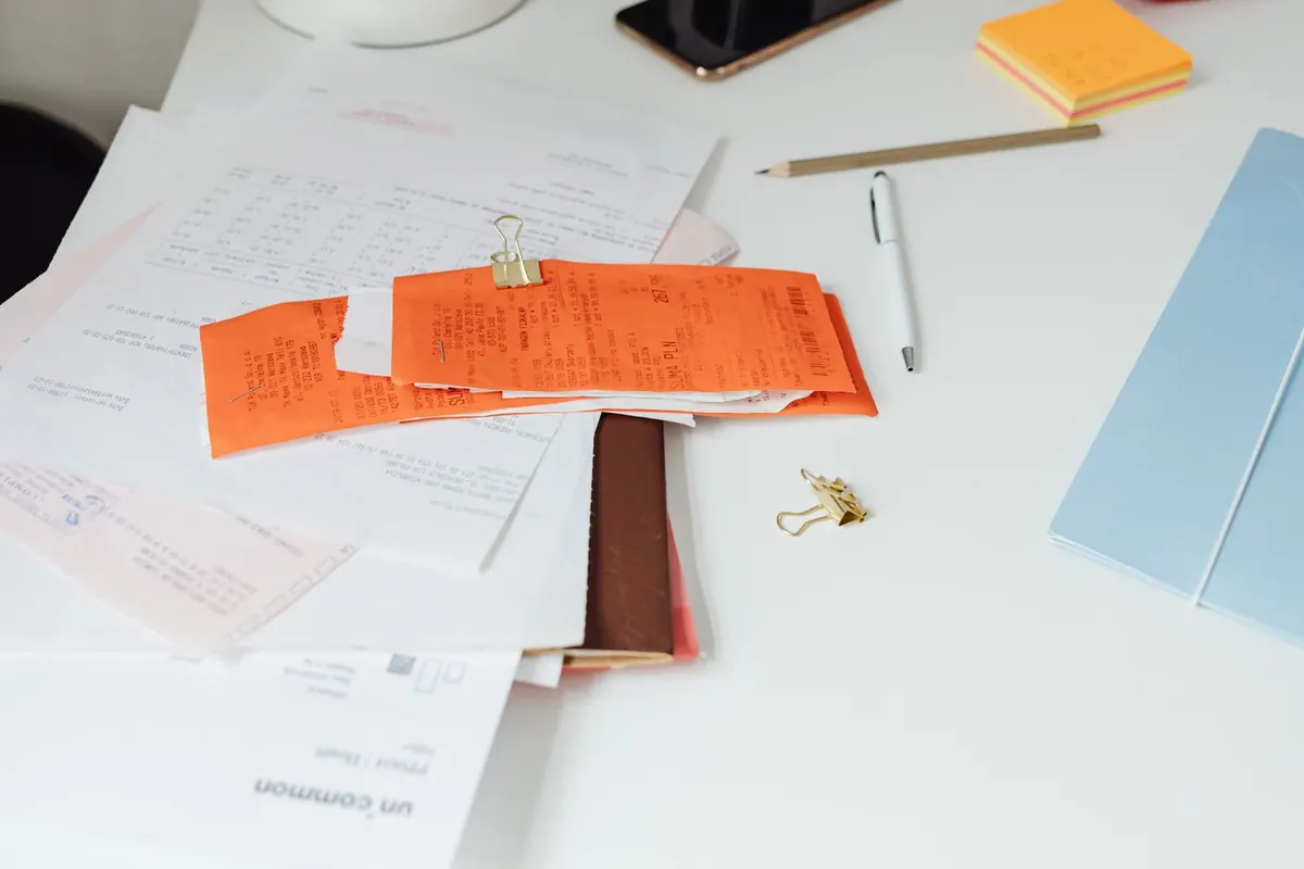 Paperwork, receipts and stationery spread across a desk