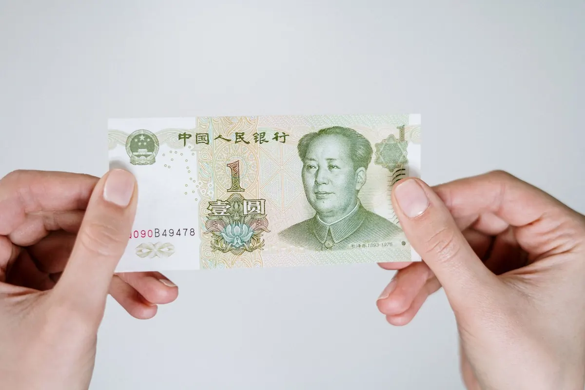 A pair of hands holding a one yuan banknote up to the light
