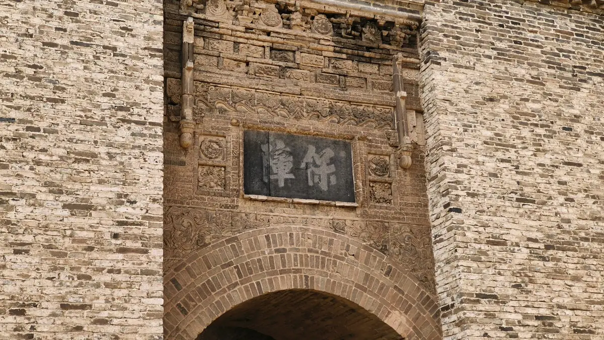 A carved stone archway in an old Chinese walled town.