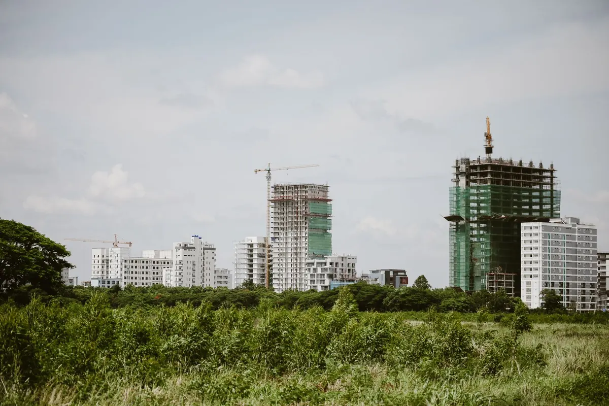 Tower cranes over apartment blocks under construction on a city skyline.