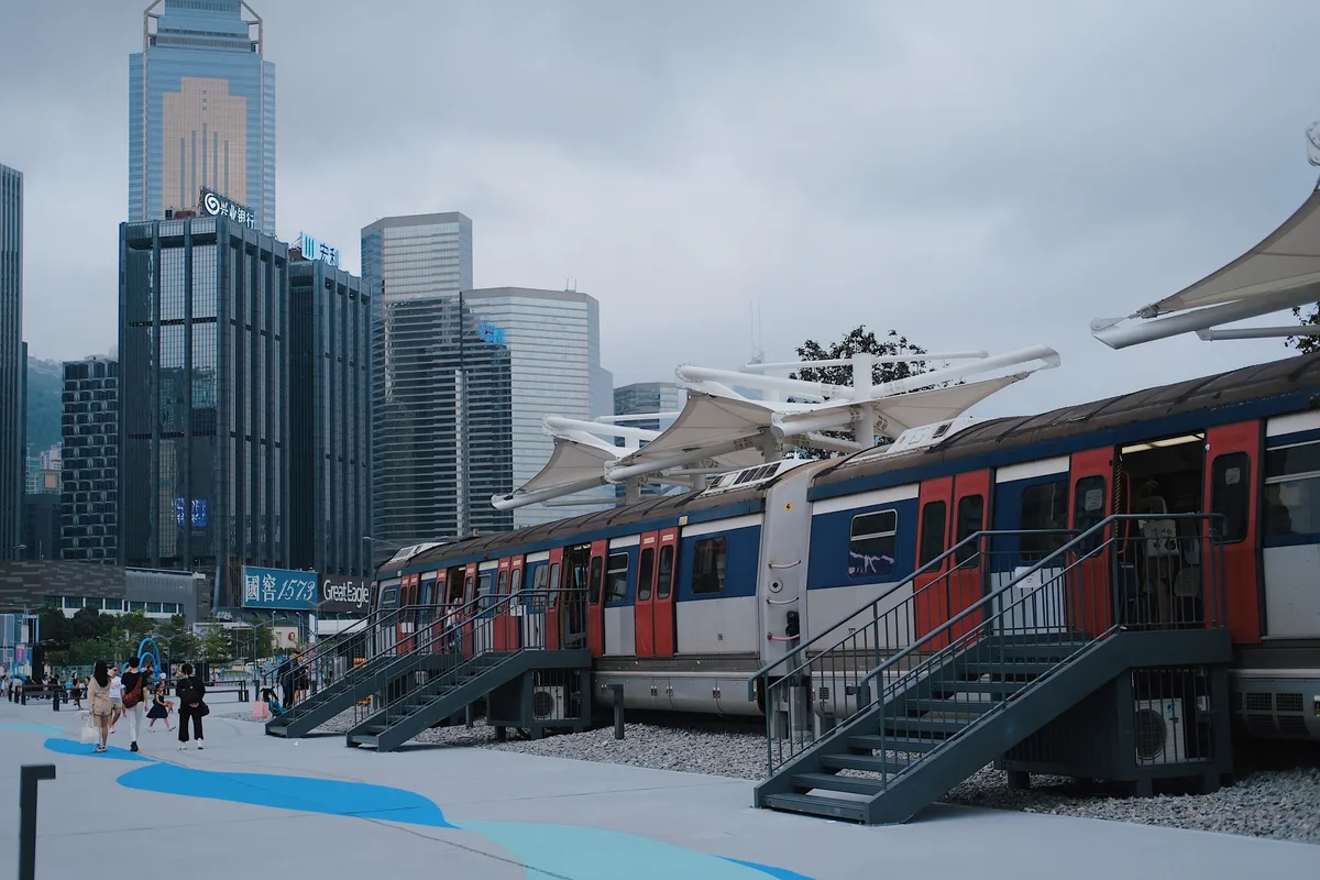 An urban train platform with the Hong Kong skyline behind it.