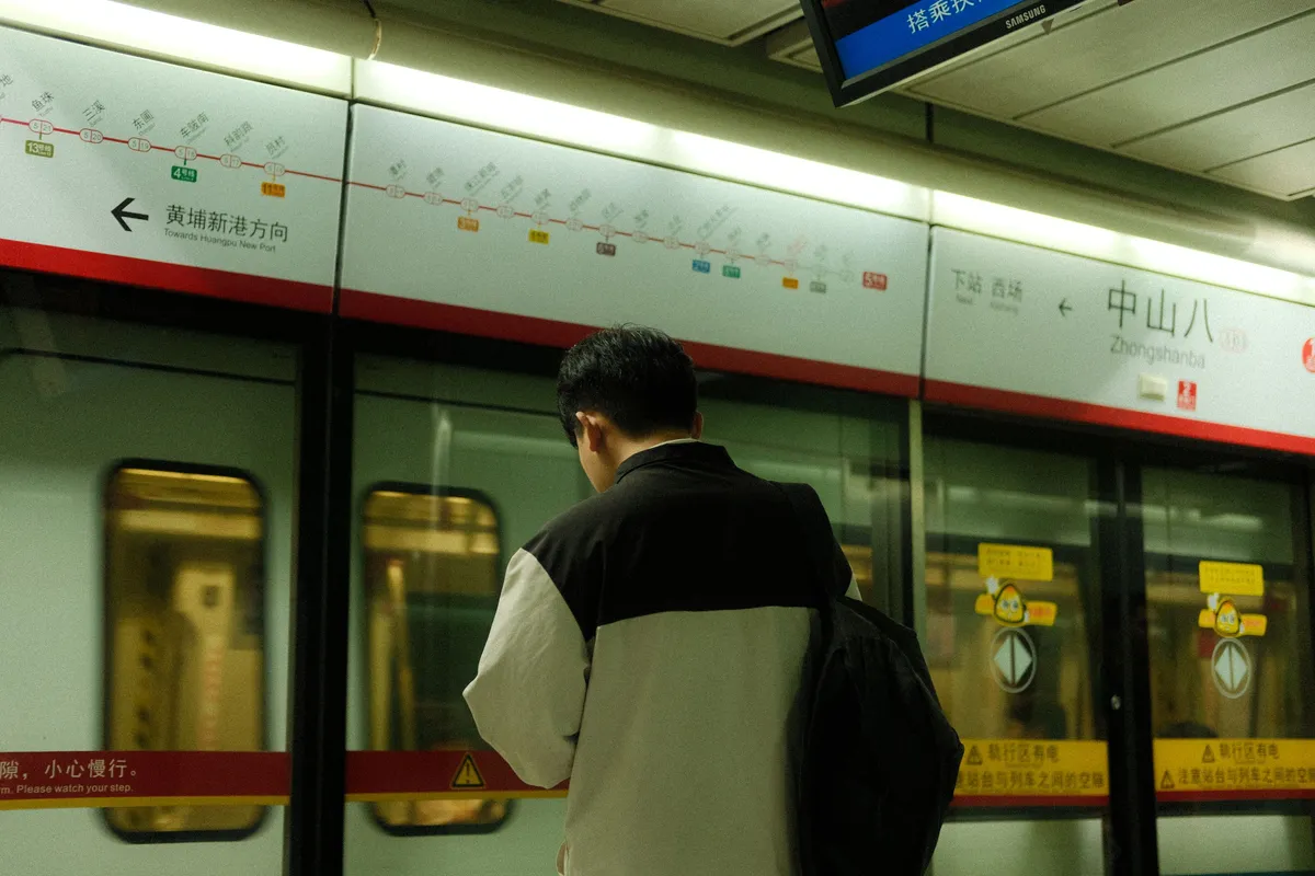 A man waiting on a platform at a Chinese subway station.