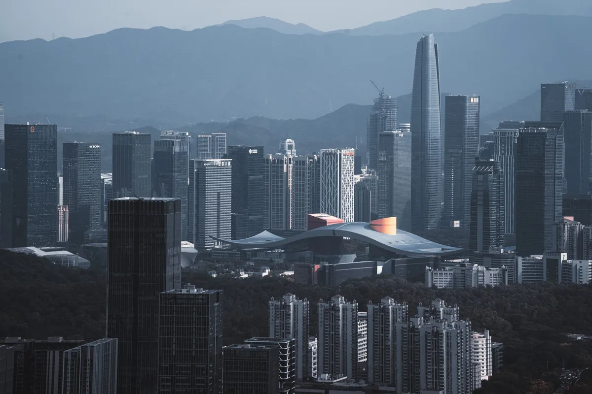 Aerial view of the Shenzhen skyline at dusk, towers lit against a darkening sky.
