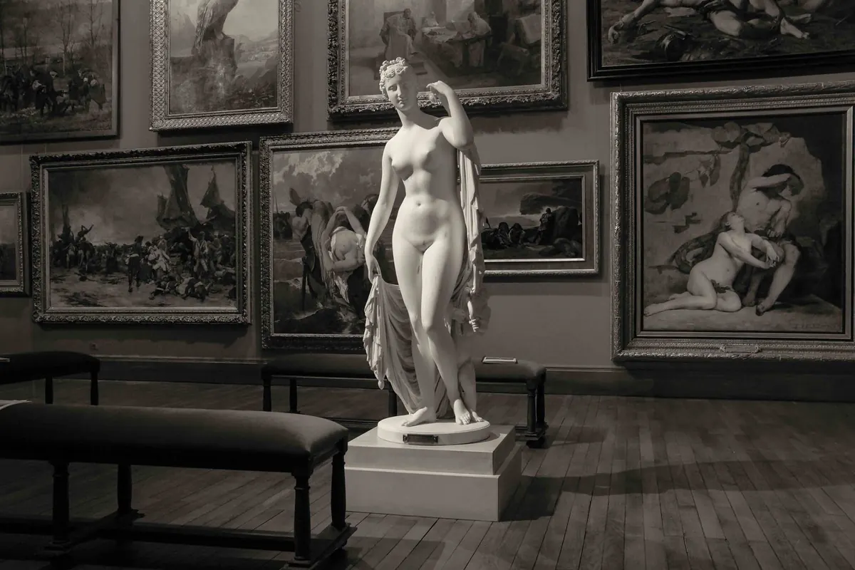 Stock photograph in grayscale of a sculpture on a plinth in a French art gallery.