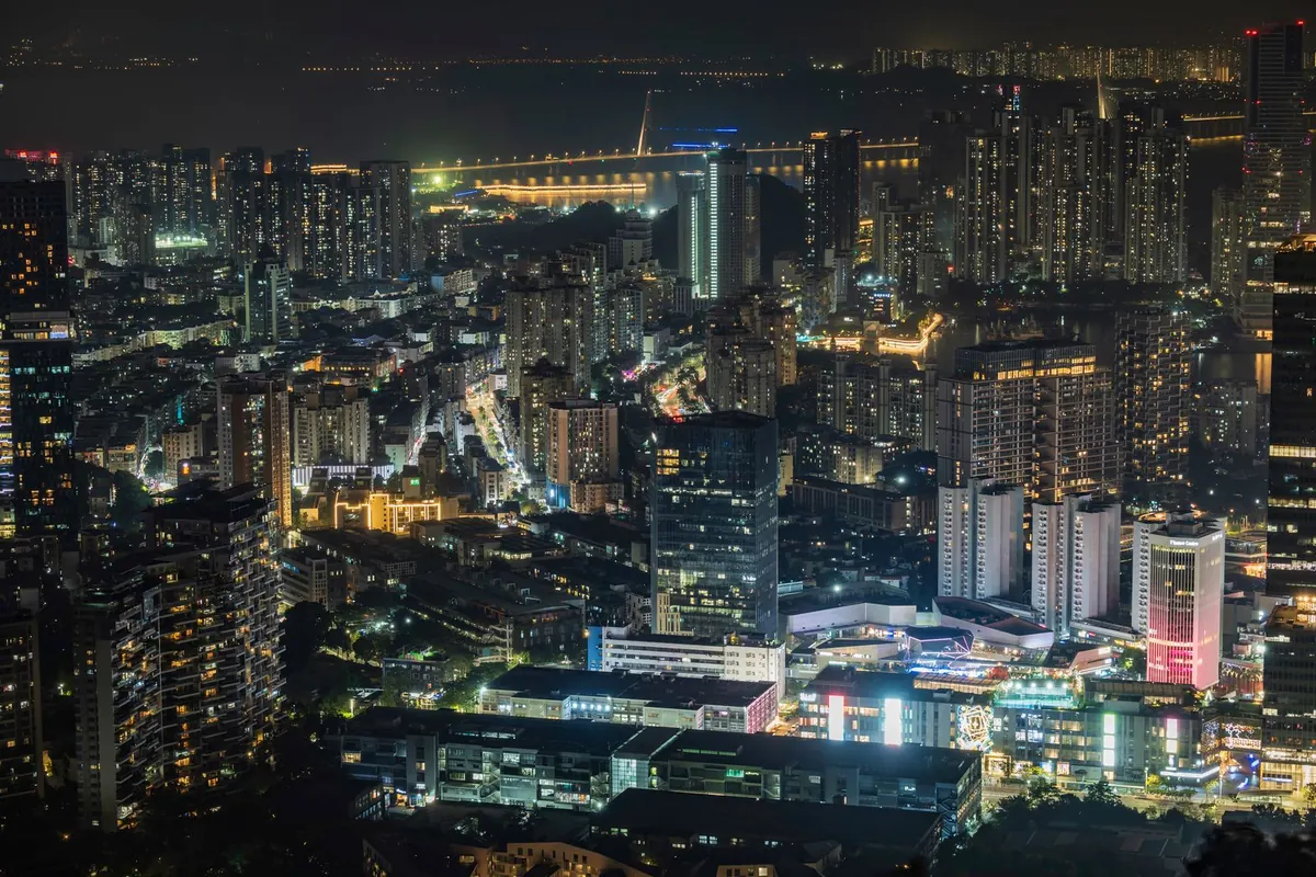 Stock aerial photograph of a Chinese city at night, towers and lit highways. Not Longgang.