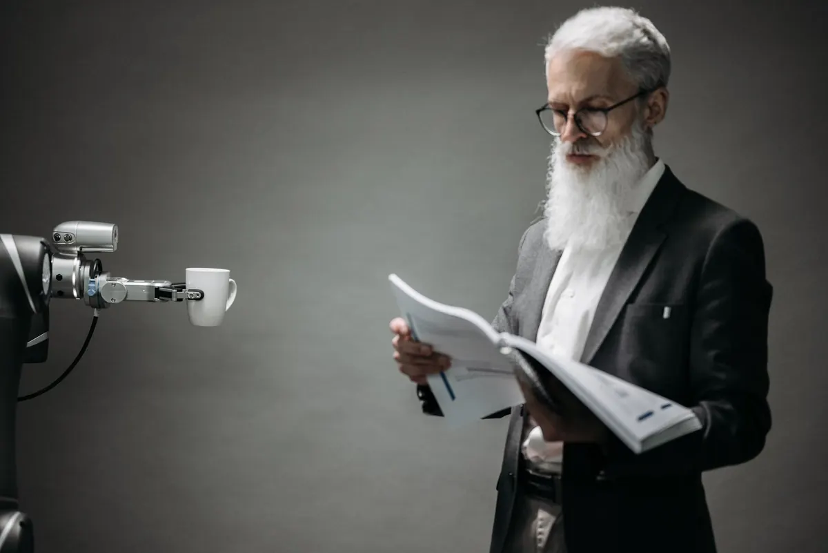 Stock photograph of a robotic arm beside a coffee cup on a desk.