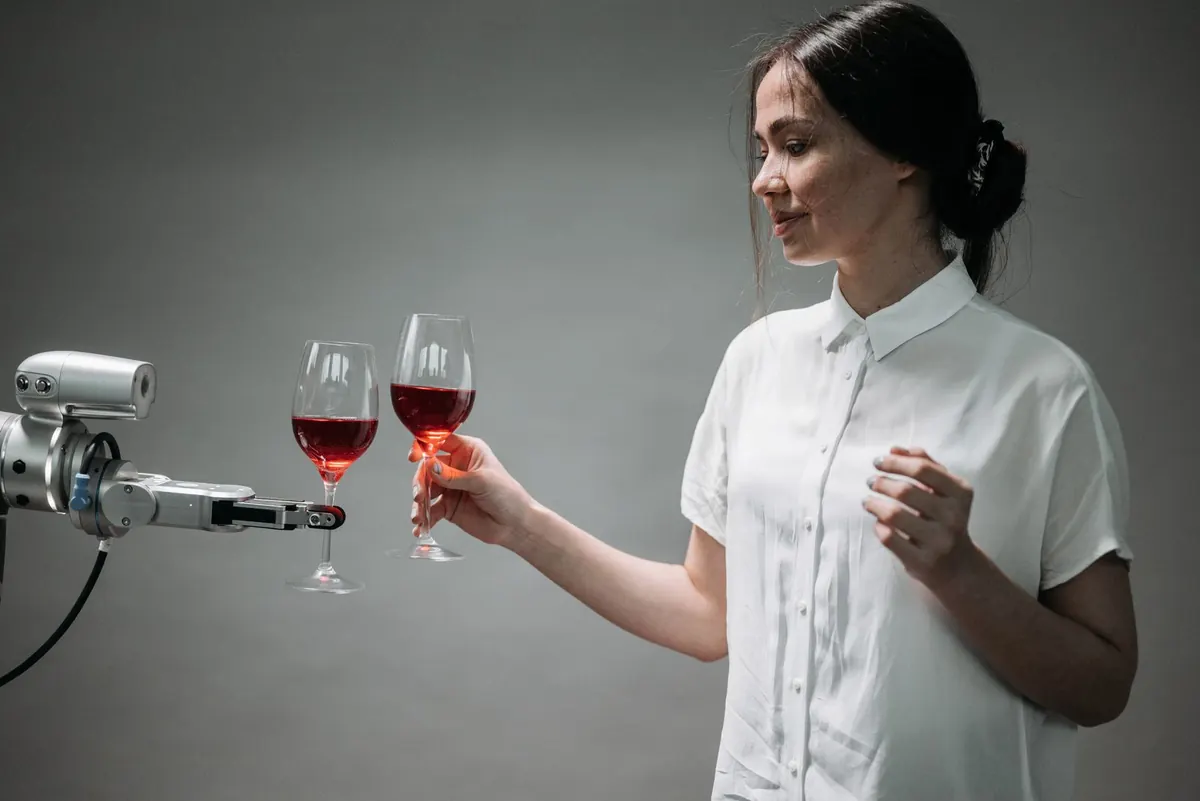 Stock photograph of a person and a robotic arm holding wine glasses.