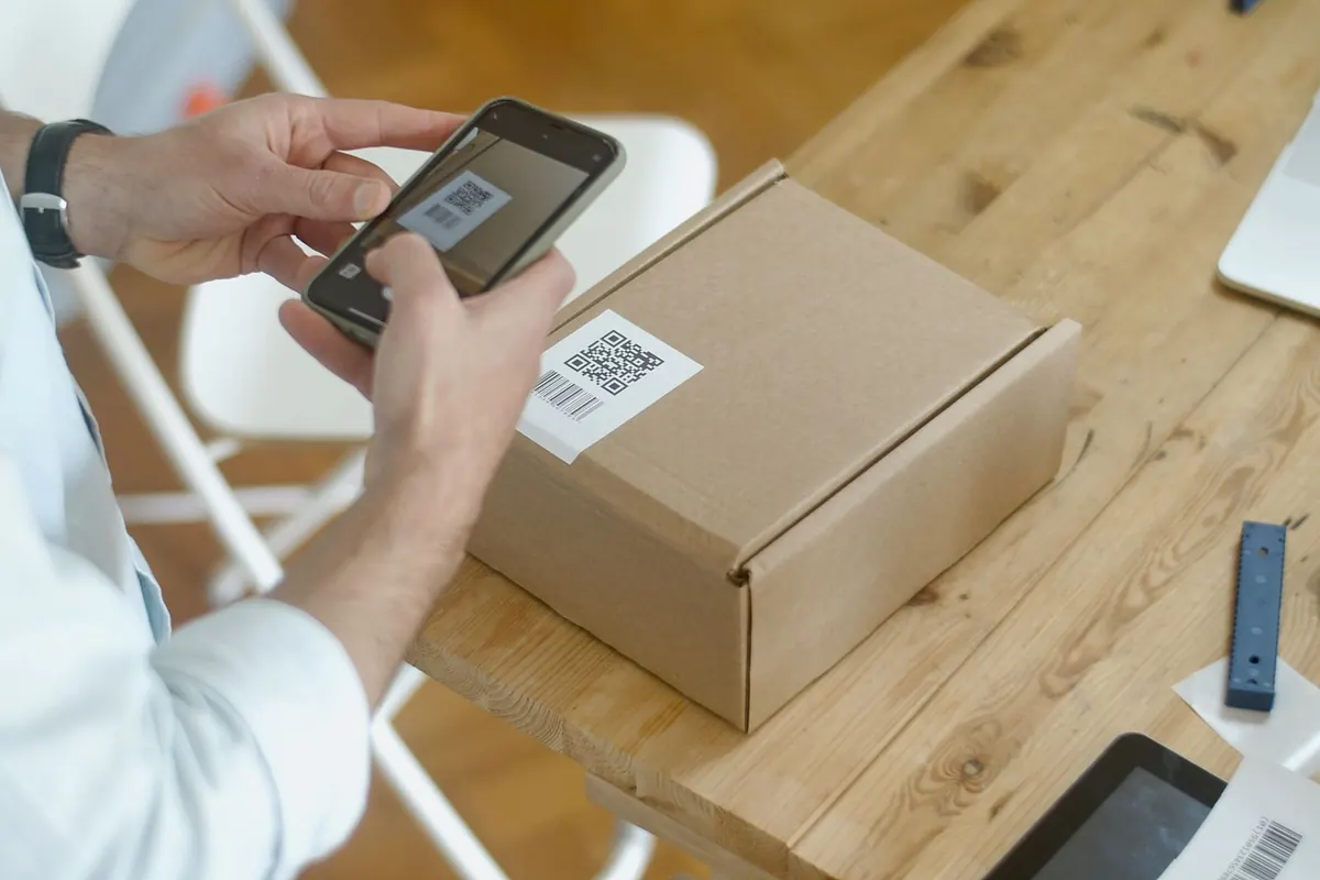 A hand holding a smartphone to scan a printed QR code