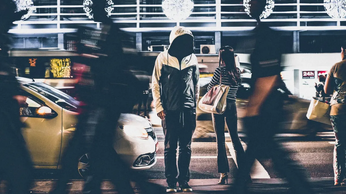 Pedestrians crossing a city street at night, caught in motion blur