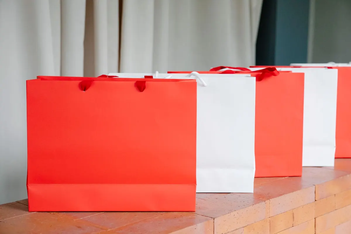 Red and white paper shopping bags lined up on a counter