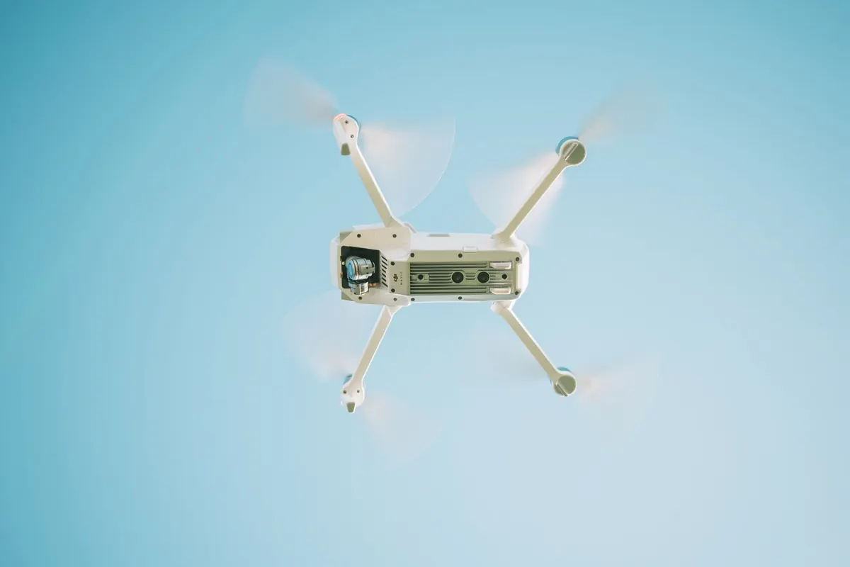 A white quadcopter drone in flight against a clear sky